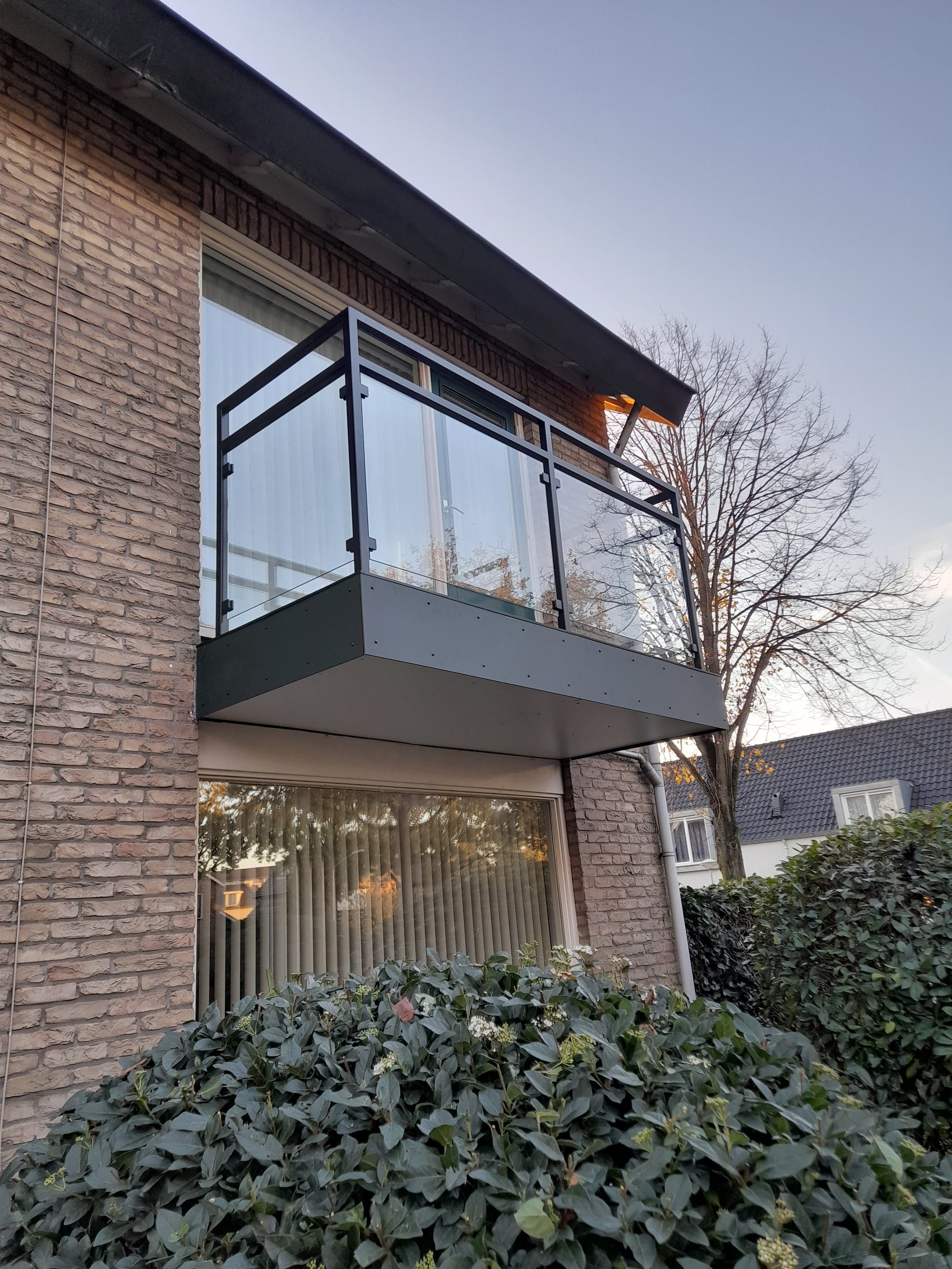 Stalen overkapping met glazen dakpanelen gemonteerd aan een woning