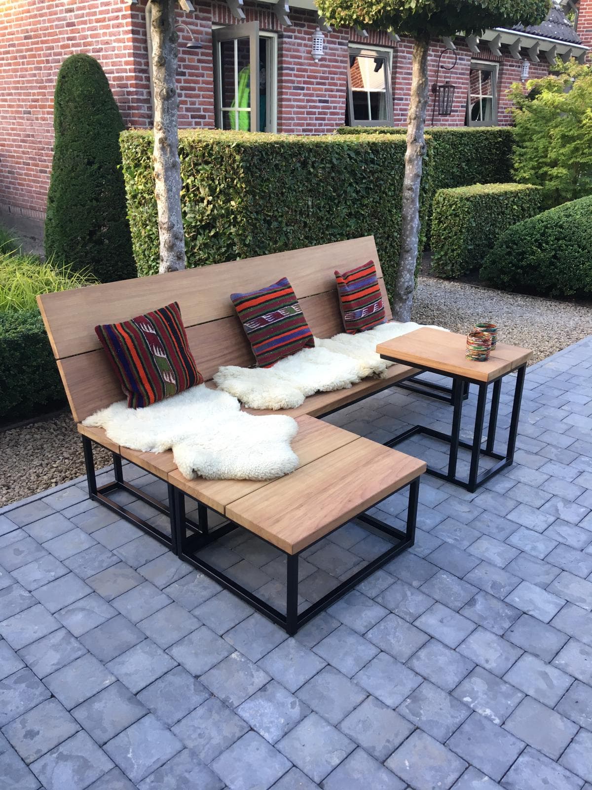 Maatwerk tuinbank en bijzettafels met stalen frames en houten zitting in een tuin